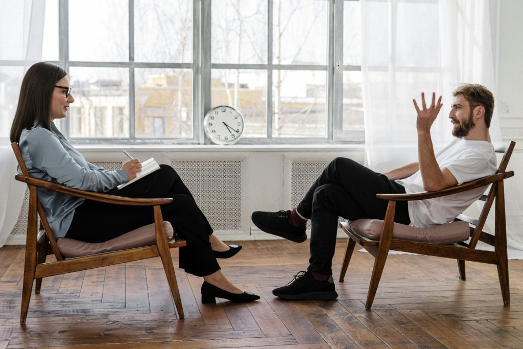 Ein Therapeut führt eine Beratungssitzung mit einem männlichen Patienten durch, um seine psychische Gesundheit zu unterstützen.