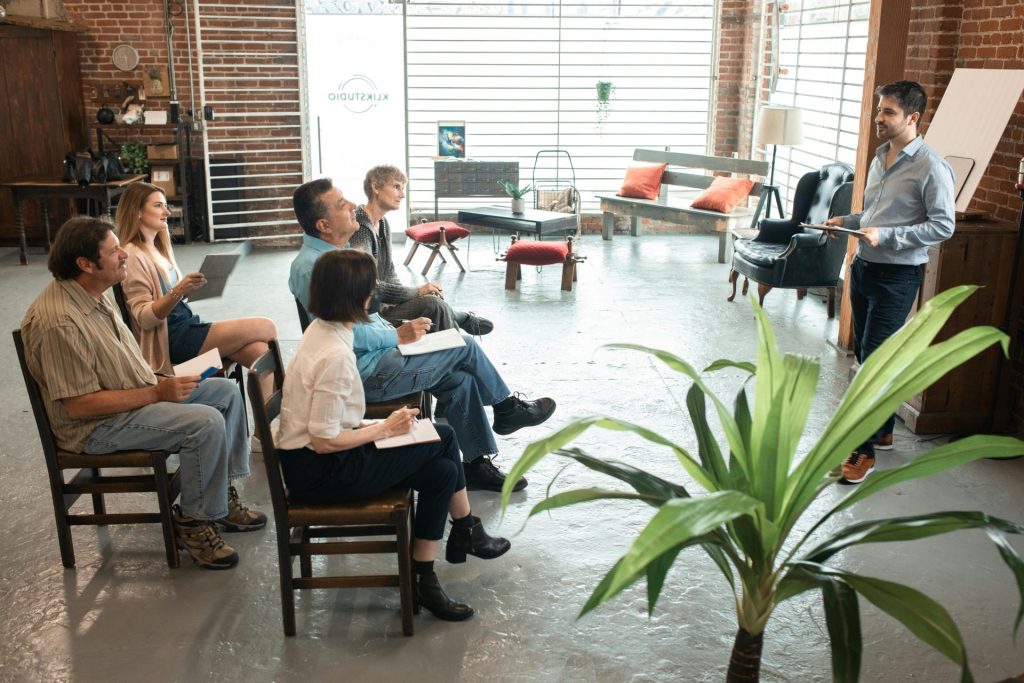 Eine bunt gemischte Gruppe von Erwachsenen nimmt an einer Workshop-Sitzung in einem trendigen Loft teil.